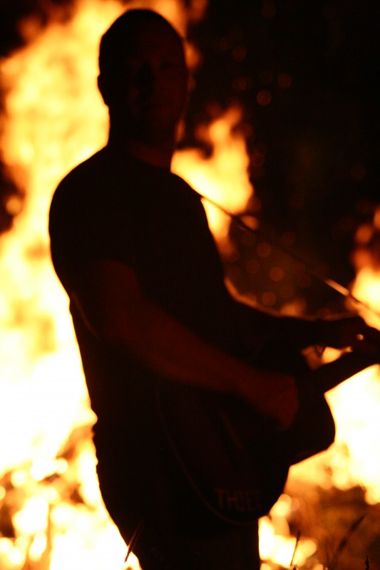 Scott Troyer playing slide guitar in front of bonfire